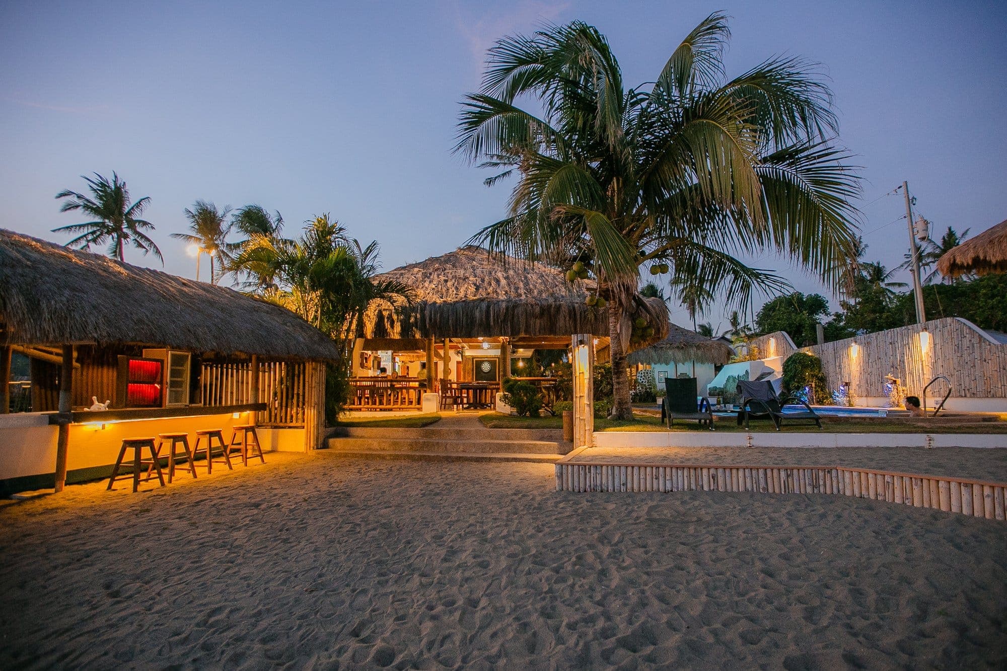The beach bar and restaurant lit warmly at dusk, ready for an evening event