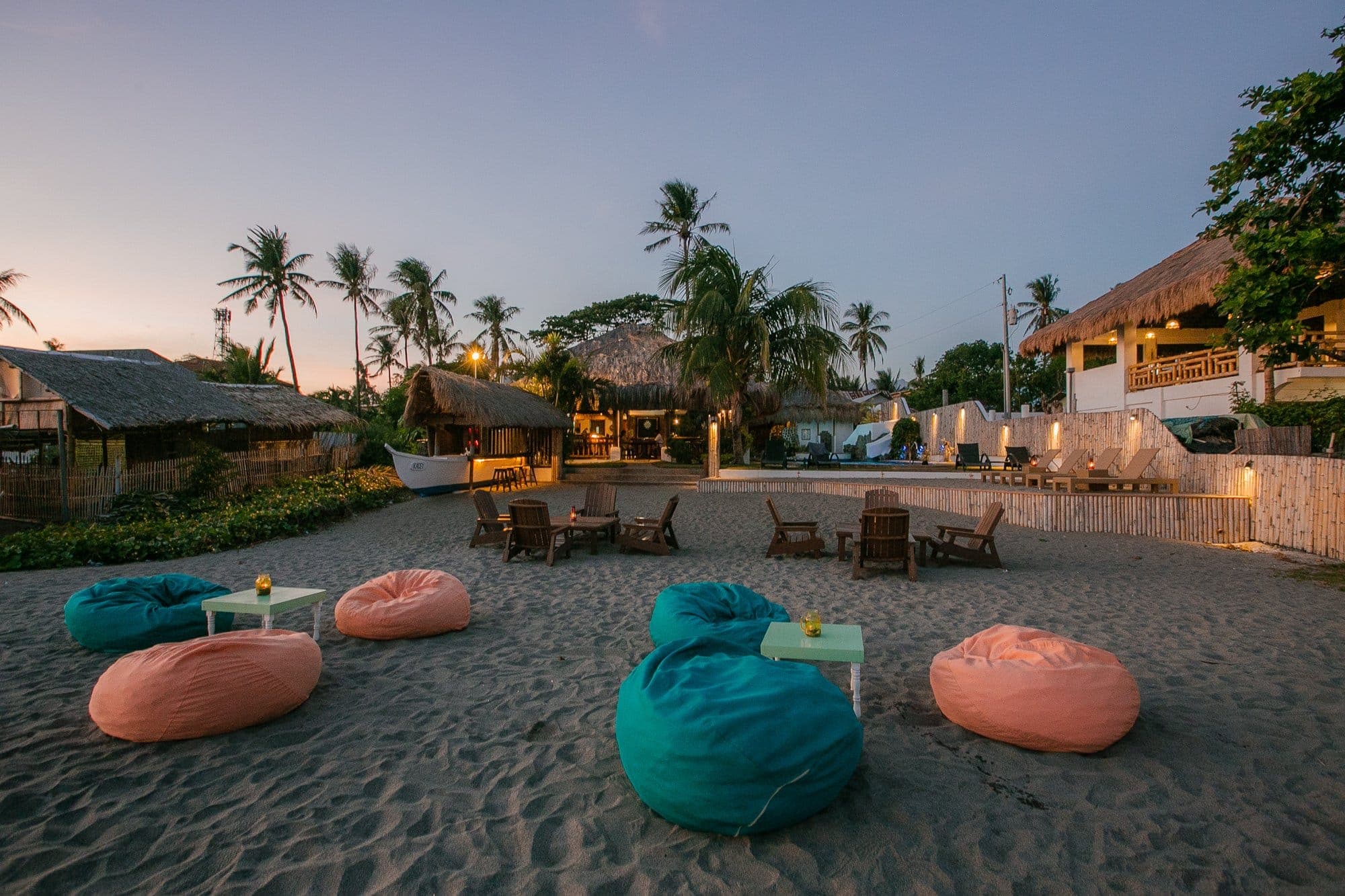 The beach at dusk set with bean bags and wooden chairs