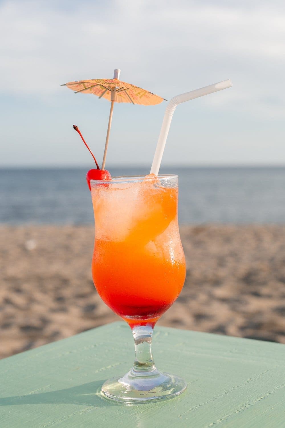 Tropical cocktail with a paper umbrella against the sea