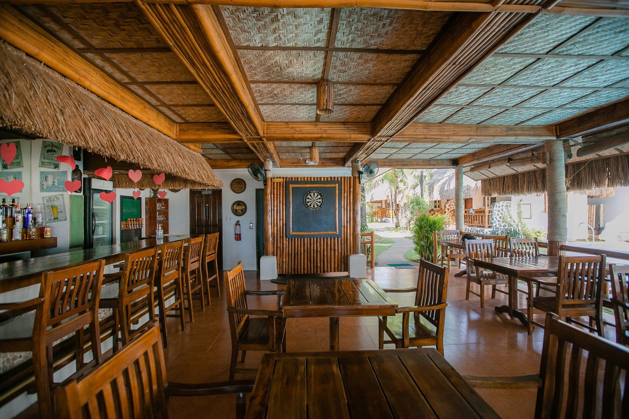 Open-air restaurant with hardwood tables under woven bamboo ceilings